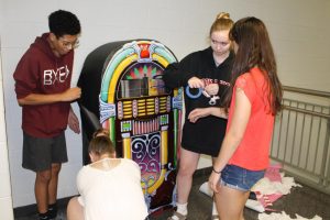 Sophomores Isaac Martin, Jamie Fadgen, Natalie Scchantz, and Amanda Wardlow work together to create a colorful, old-fashioned juke box decoration.