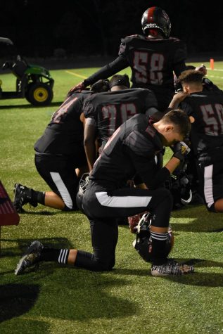 Senior Aidan Emanuel kneels on the sidelines minutes before the clock starts. To prepare for his games, Emanuel separates himself from his high-energy surroundings to pray. “I seclude myself and talk to my Lord,” Emanuel said.