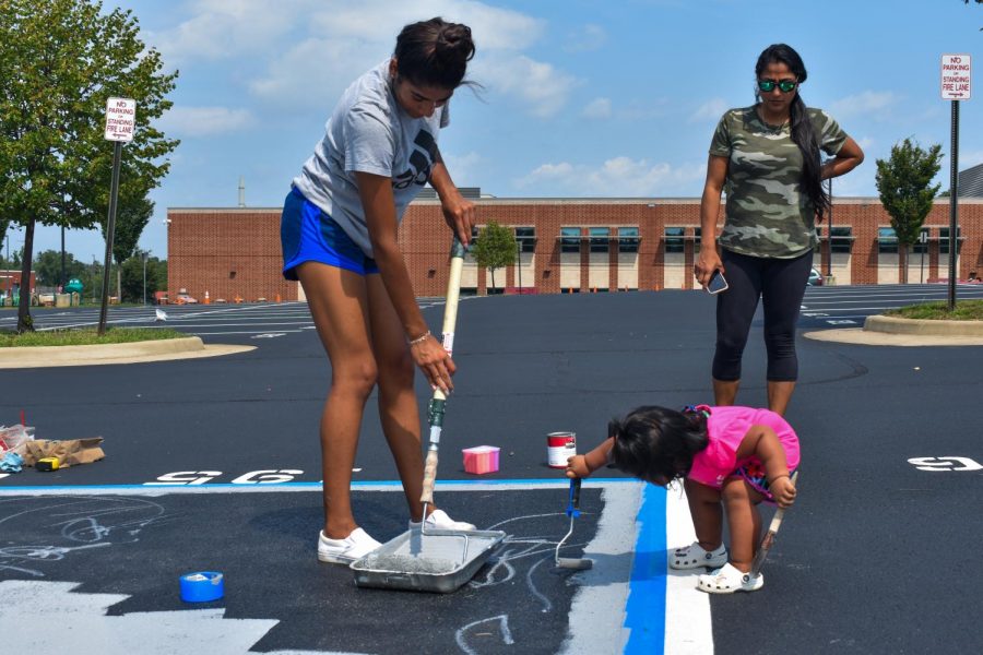 Senior Gabby Lozada rolls gray paint on her spot with her family.