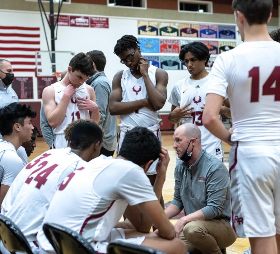 Circling around, the varsity boys basketball team circles around Geyer as he instructs them with different plays to execute during the game. 