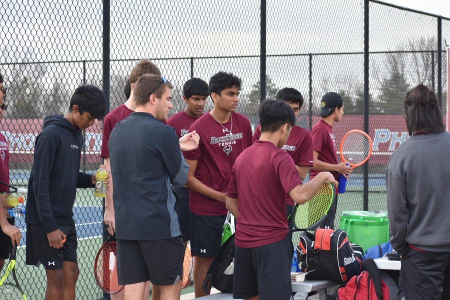 The varsity boys tennis team gathered around tennis coach Chris Schamus following their triumphant round of singles. 
