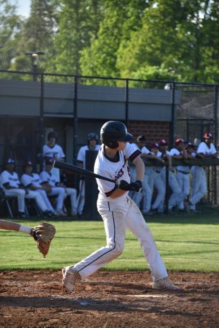 Senior Ryan Buermeyer (22), mid-swing, aims to hit the ball and allow sophomore Dylan Neach (21) and freshman Nikhil Midda (9) to make it home from second and third bases respectively.