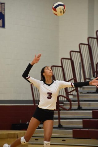 Junior outside hitter Sidney Powell jumps as she serves the ball over the net to the opposing side.