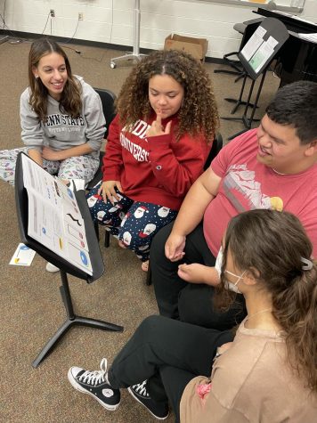 Senior Julia Freeman, sophomore Kaylie Rivers, and junior Bella Pilgreen teach senior Colby Lower how to read rhythm.