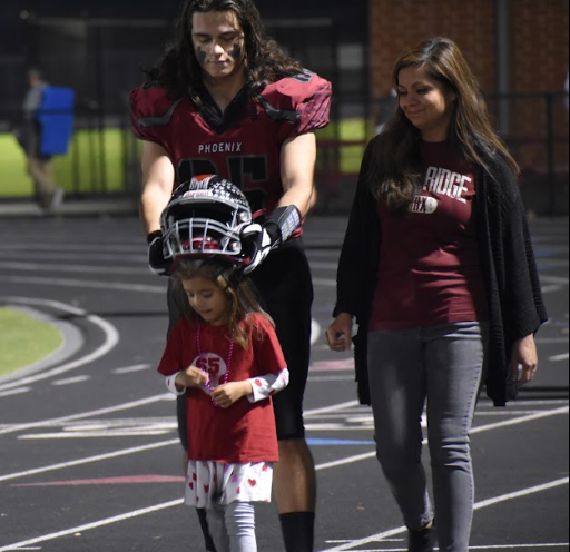 Walking down the track, senior Ethan Strine places his helmet on his sister. “It was our senior night, so I got to embrace it with my family and everything,” Strine said.