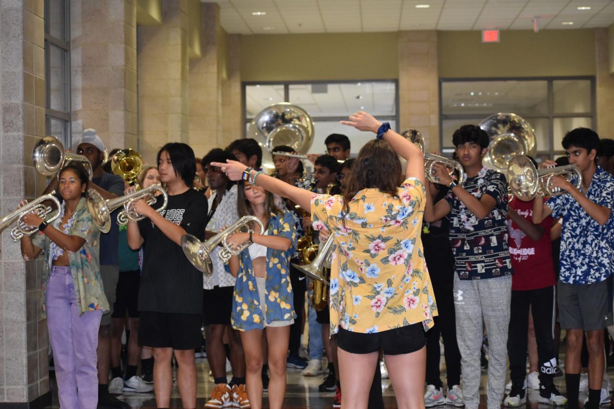 Before the first pep rally of the year, the marching band rehearses stand tunes to perform for the incoming students. Senior drum major Bella Pilgreen directs the band members to move their instruments left and right during the percussion break in their cover of “Power” by Ye (formerly Kanye West).