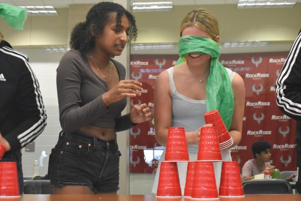 Junior Ruth Gemechu guides her blindfolded partner, junior Kailyn Fetterman, as they try to stack cups. 