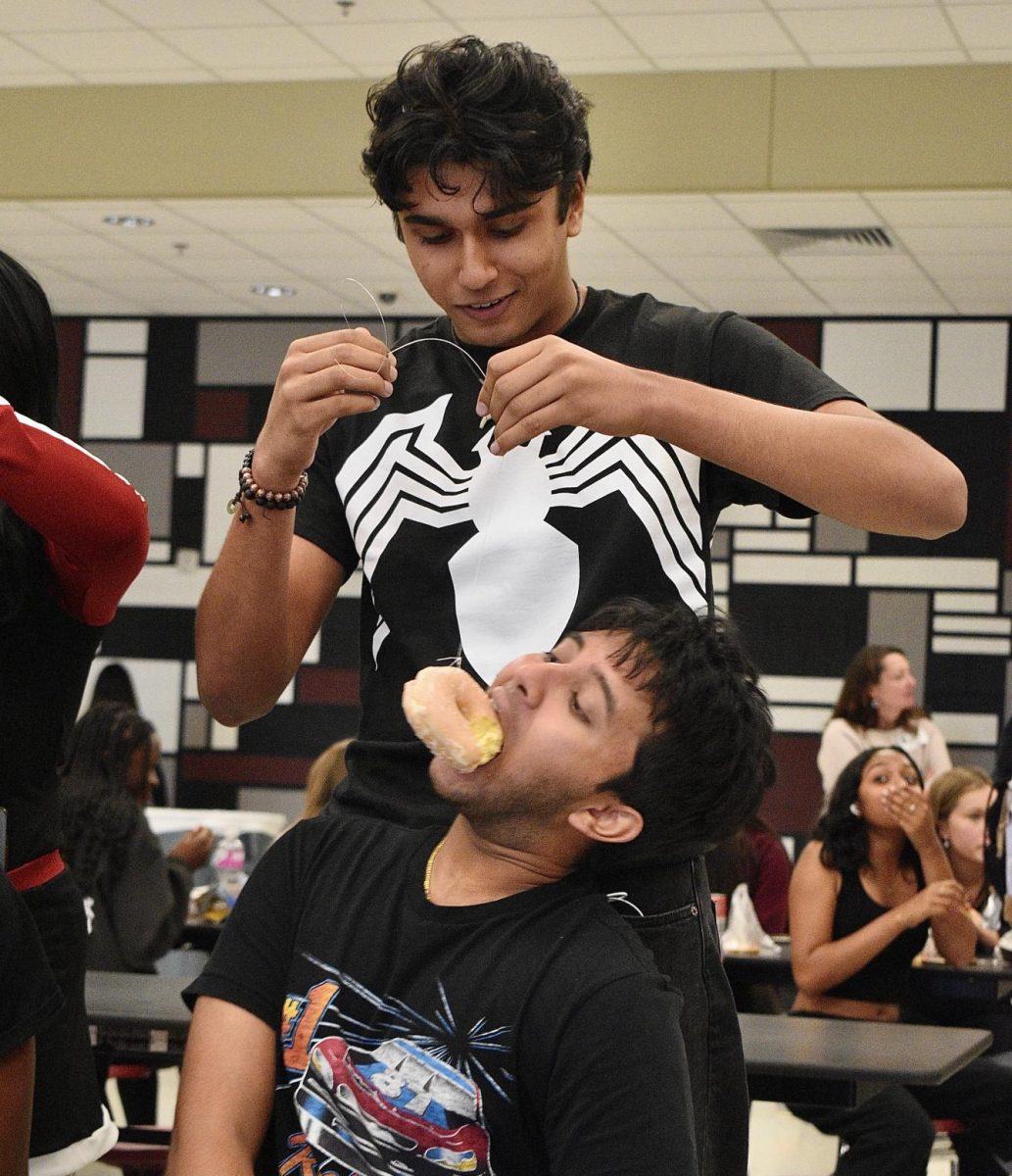 Seniors Hari Kommu and Raushan Goureddy participate in the donut lunch game on Friday, Sept. 29, attempting to be the first team to fully eat the sugary dessert. Kommu and Goureddy ultimately came in second, however, and the junior team claimed the victory.