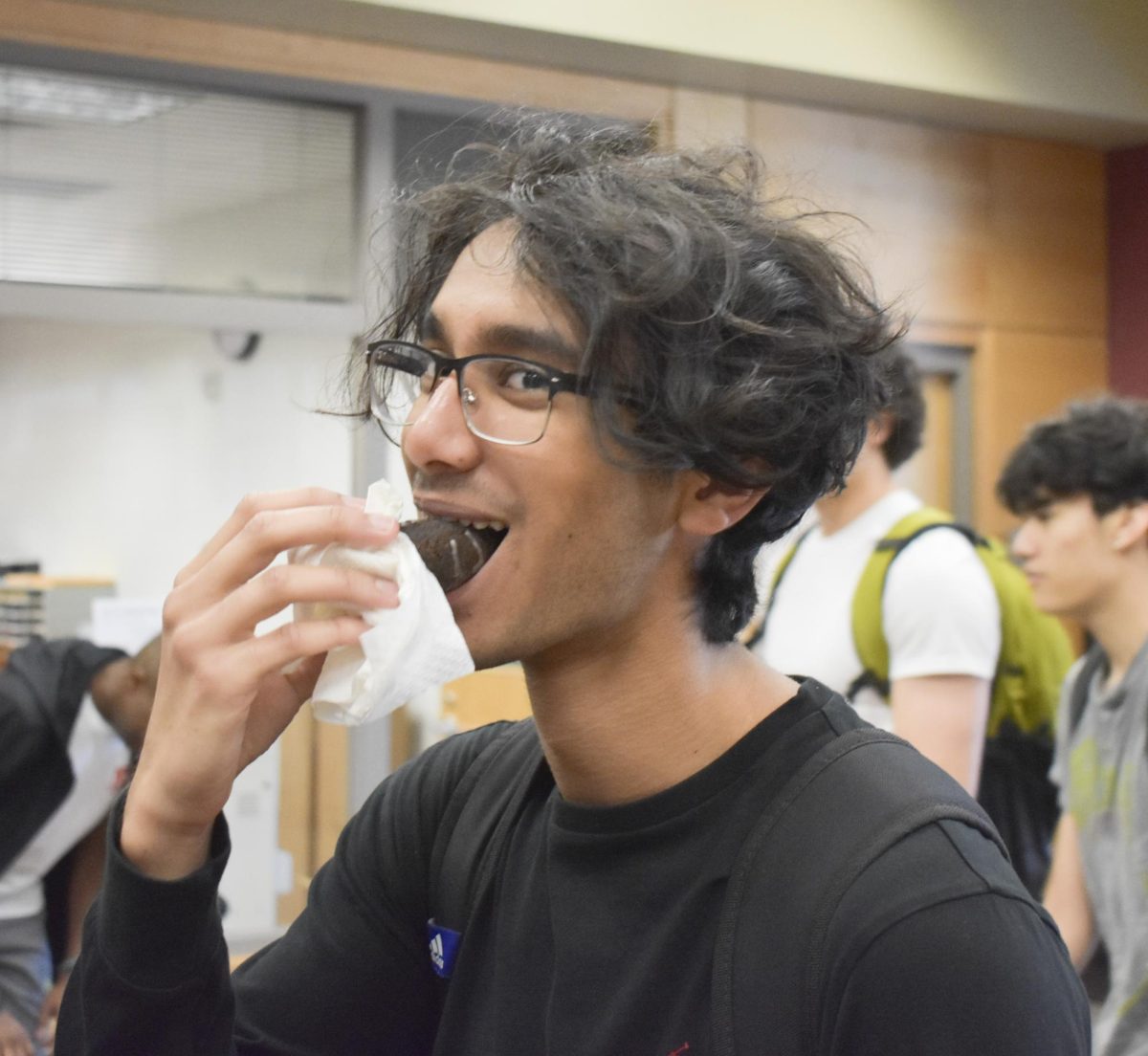 Senior Jawad Bhullar munches on a chocolate donut at the senior breakfast.  From glazed, chocolate with or without sprinkles, yellow frosted, a  variety of different donuts were available for seniors to enjoy.
