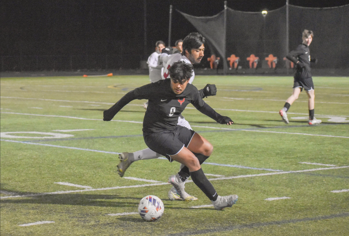Senior Arshan Shahjahan pushes past a Spartan defender as he dribbles the ball.