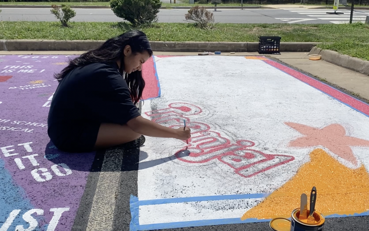 Senior Pranjal Deshmukh carefully applies paint to the outline of her name on a Barbie box parking spot design. At the annual parking spot painting event, rising seniors got a chance to claim a parking spot; brainstorm a personal design; come equipped with gallons of paint, various brushes, and rolling pins; and have fun coloring the asphalt with friends and family. 
