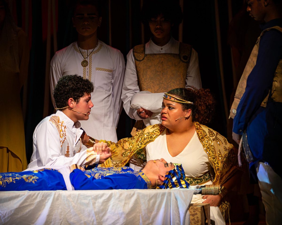 Ramses, played by junior Andres Marrero, and Tuya, played by senior Kaylie Rivers, hug each other in their grief after saying goodbye to the dying Pharaoh Seti, played by Palmer Joly. In the play, Ramses, who recently got appointed Viceroys, is left with the title and power of Pharaoh and the responsibility of leading Egypt after his father’s death.  
Photo Courtesy of Scott Sikes