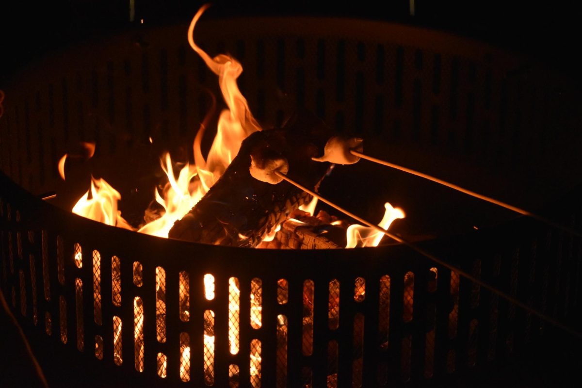 Students roast marshmallows over the fire pit, ready to make smores and watch “Home Alone 2” during the Frost Fest.