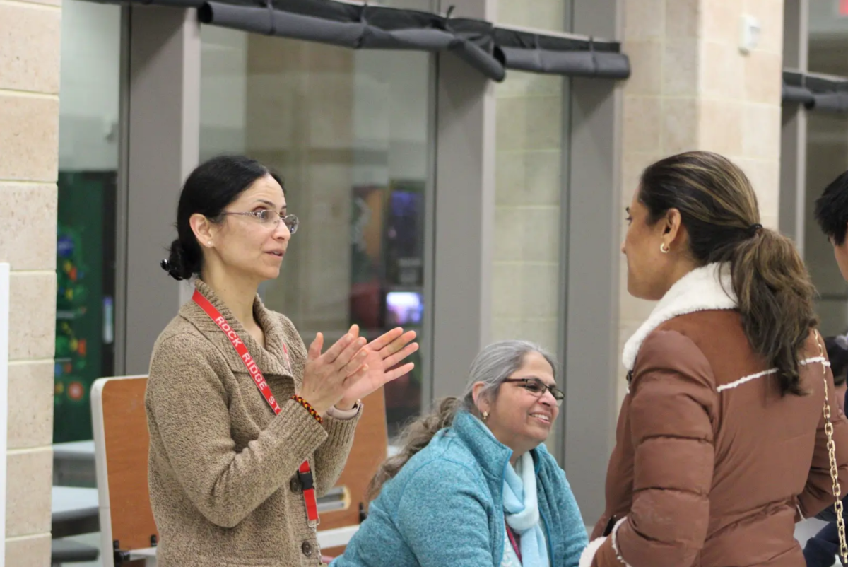 Biology teacher Anshu Jaiswal speaks animatedly with a parent about the different science courses available for the grade levels.