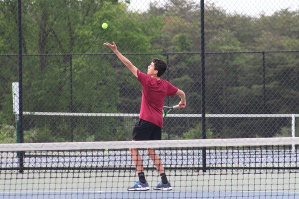 Freshman Christian Bhide serves a ball during his singles match.